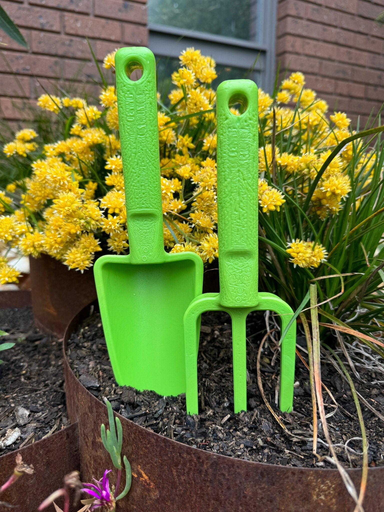 green-hand-trowel-and-green-hand-fork-recycled-plastic-garden-toolset-in-garden