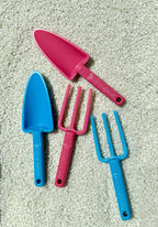 Pink-and-blue-kids-garden-tools-laying-on-recycled-plastic