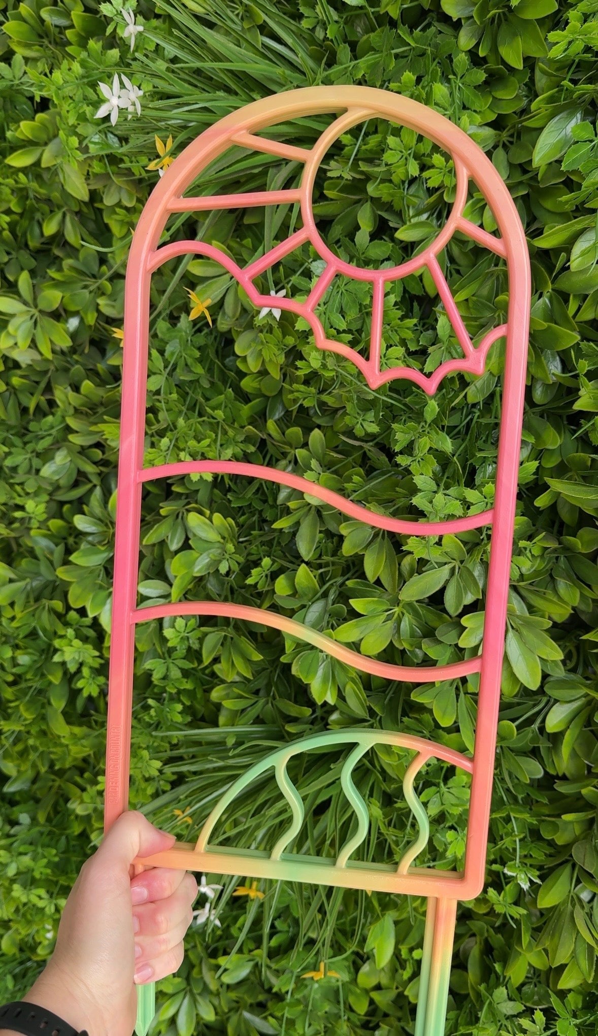 Colourful recycled plastic plant trellis  against a green leafy background